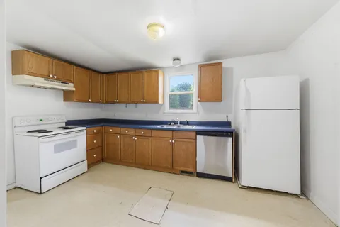a kitchen with granite countertop appliances a sink and a refrigerator