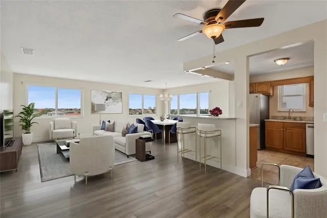a living room with furniture kitchen view and a wooden floor
