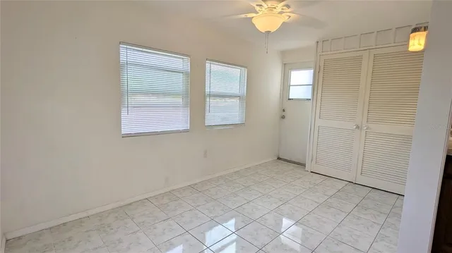 an empty room with windows and chandelier fan