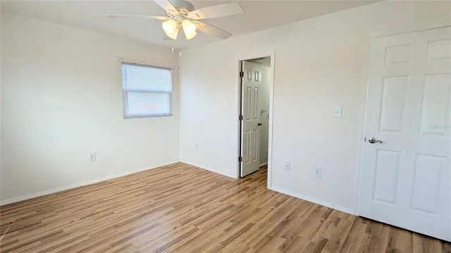 an empty room with wooden floor fan and windows
