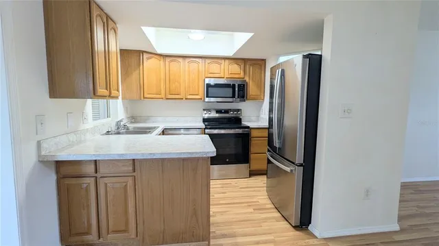 a kitchen with kitchen island granite countertop a refrigerator stove microwave and sink