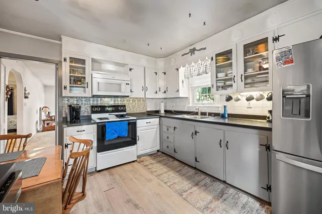 a kitchen with stainless steel appliances granite countertop a stove top oven a sink a dining table and chairs with wooden floor