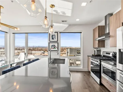 a kitchen with stainless steel appliances a stove a sink dishwasher a refrigerator and a dining table with wooden floor