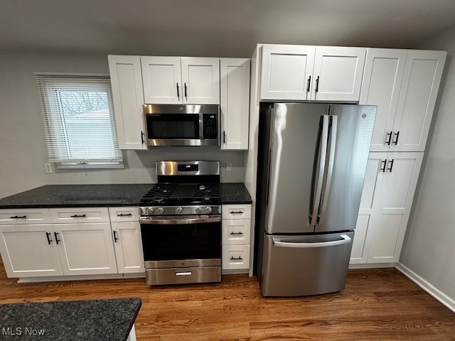 9109 Johnnycake Ridge Road Mentor, OH 44060 - Photo 19 of 28 Kitchen with stainless steel appliances, white cabinets, dark stone counters, and dark wood finished floors