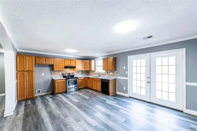 a large kitchen with lot of counter top space and wooden floor
