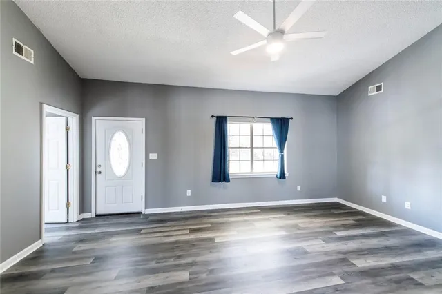an empty room with wooden floor and windows