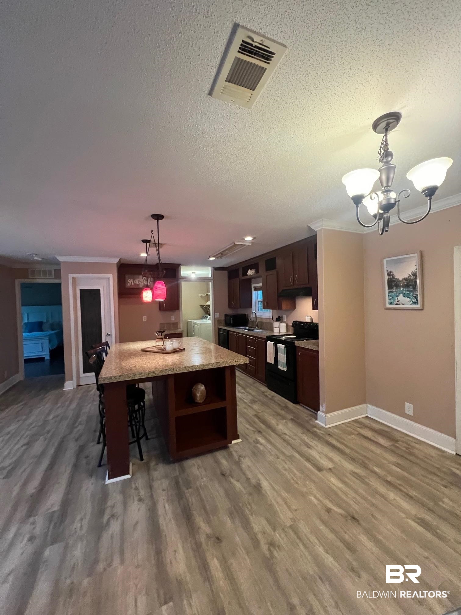 1985 Ridgewood Drive South Lillian, AL 36549 - Photo 6 of 40 Kitchen with a kitchen island with sink, dark brown cabinets, decorative light fixtures, electric range, and a breakfast bar