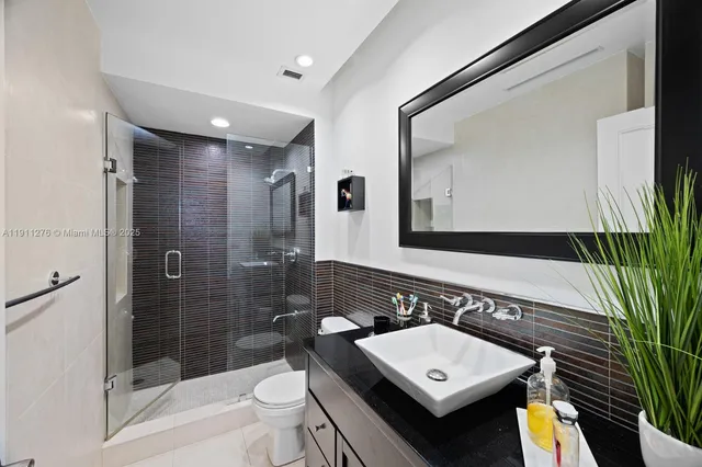 a bathroom with a sink a toilet a mirror and shower