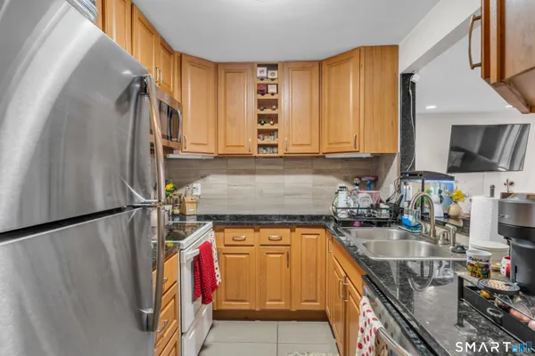 a kitchen with stainless steel appliances granite countertop a sink a stove and a refrigerator