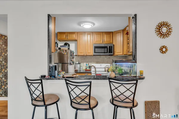a kitchen with stainless steel appliances a dining table chairs and a refrigerator
