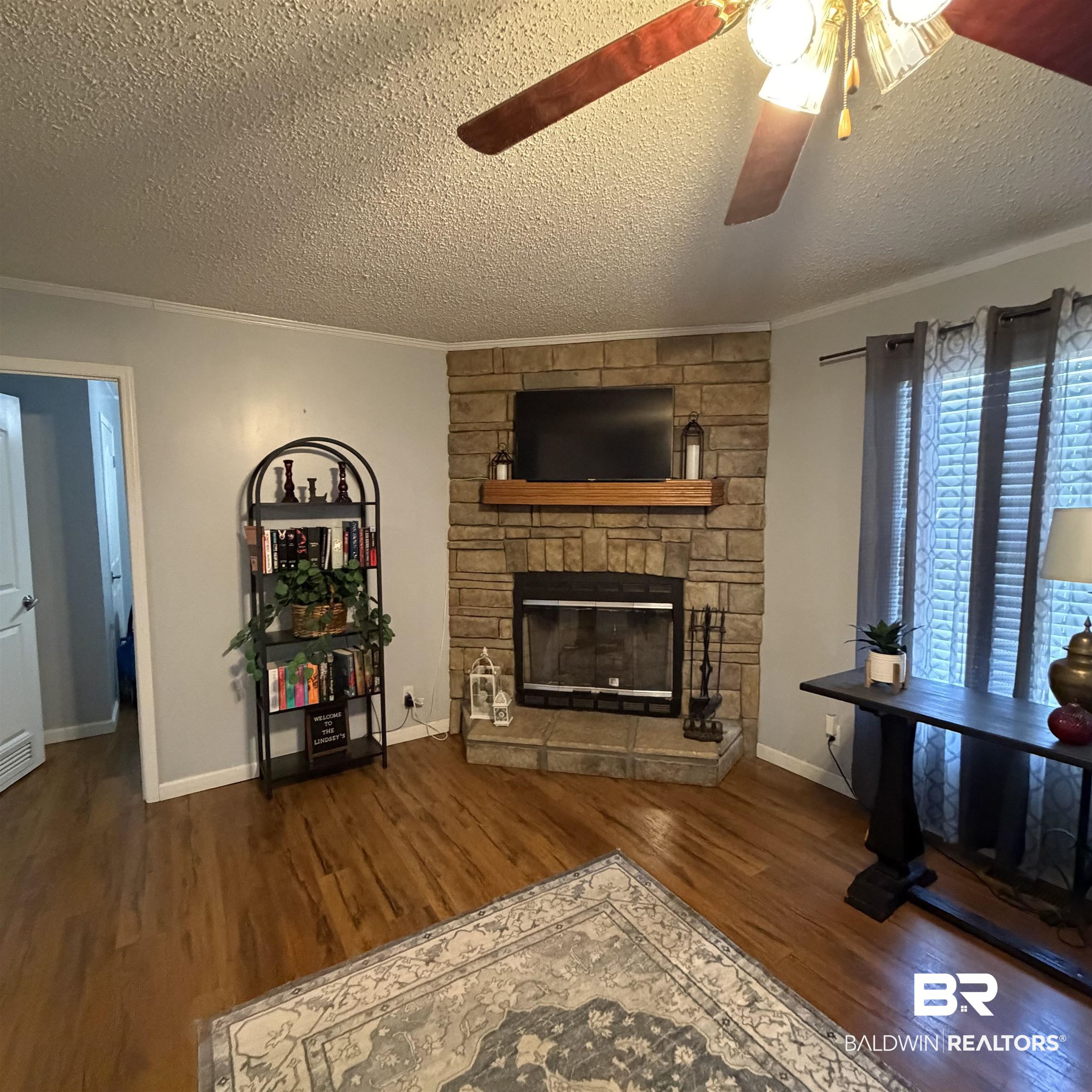 447 Sugar Hill Road Monroeville, AL 36460 - Photo 11 of 27 Living area with ceiling fan, dark wood finished floors, a textured ceiling, ornamental molding, and a fireplace