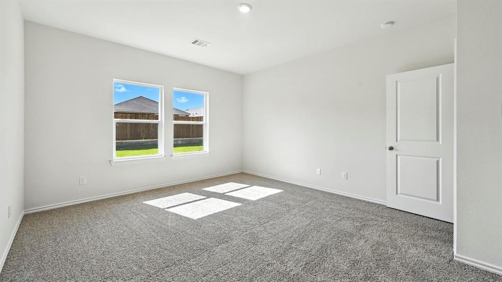 122 Pheasant Run Road Terrell, TX 75160 - Photo 10 of 36 Spacious room with plush gray carpet, bright white walls, two large windows, a two-panel interior door, and recessed lighting