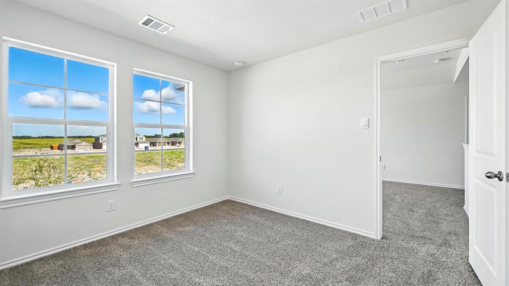 122 Pheasant Run Road Terrell, TX 75160 - Photo 17 of 36 Bright room featuring two large windows with white trim, soft gray carpet, white walls, recessed lighting, and a white interior door with black hardware