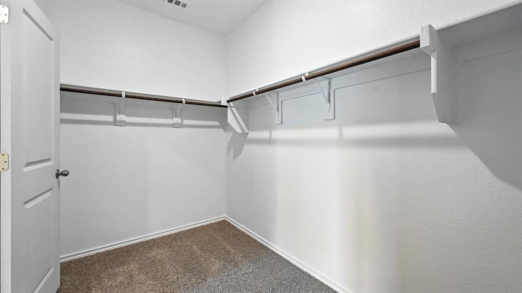 122 Pheasant Run Road Terrell, TX 75160 - Photo 19 of 36 Walk-in closet featuring white walls, deep brown carpeting, and extensive built-in shelving with hanging rods