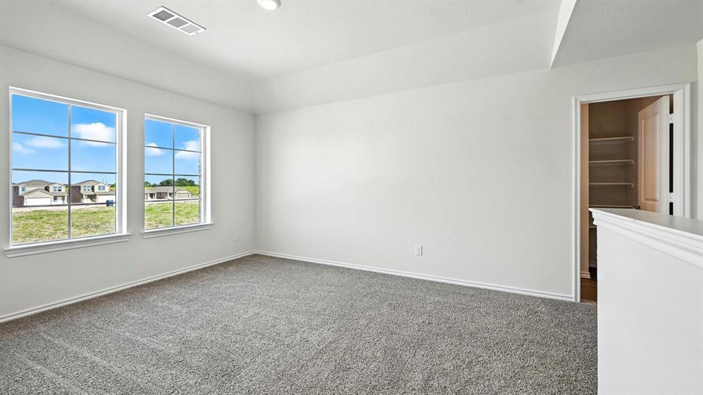 122 Pheasant Run Road Terrell, TX 75160 - Photo 24 of 36 Spacious room featuring neutral carpeting, white walls, two large windows with grid patterns, a tray ceiling, and an open doorway revealing built-in shelving
