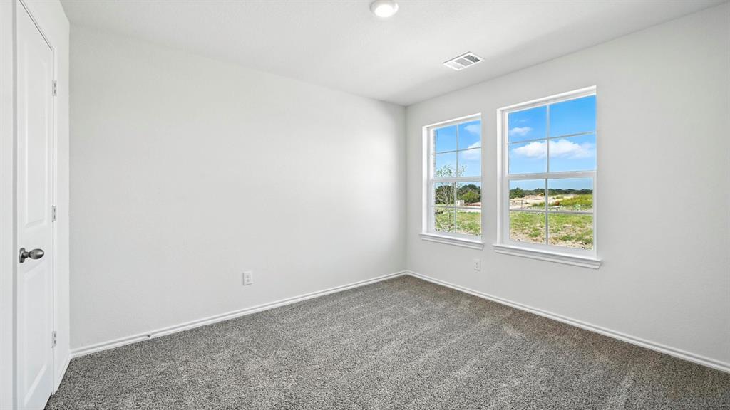 122 Pheasant Run Road Terrell, TX 75160 - Photo 25 of 36 Room featuring two double-hung windows, a white paneled door, gray carpet, white baseboards, and a flush-mount ceiling light