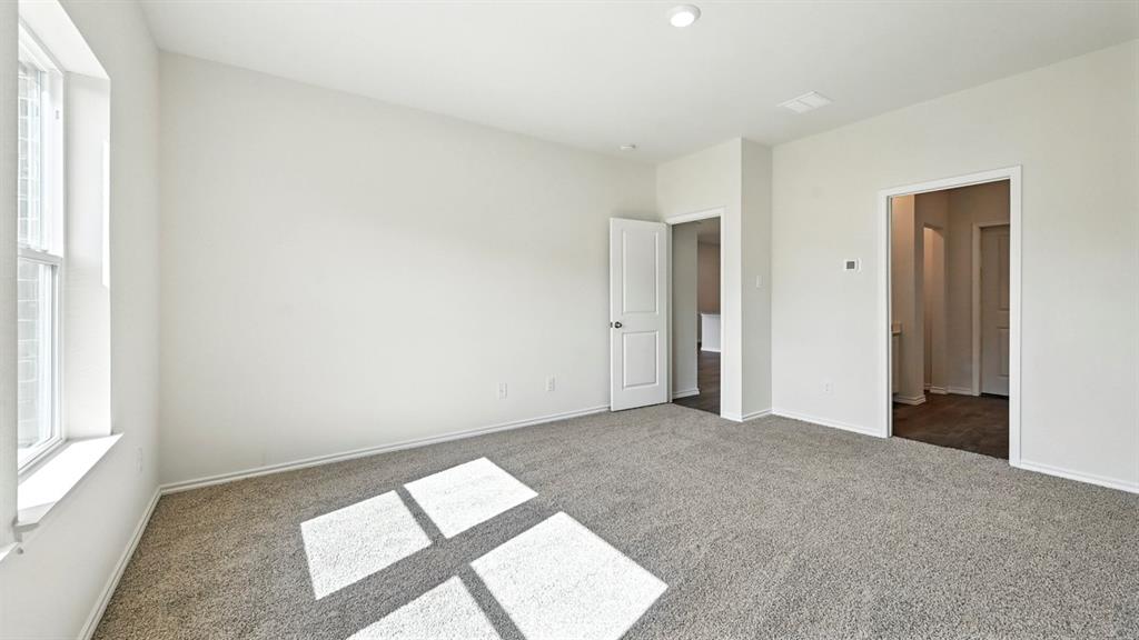 122 Pheasant Run Road Terrell, TX 75160 - Photo 9 of 36 Spacious room featuring neutral carpeting, white walls, a large window, a ceiling-mounted light fixture, and two interior doorways