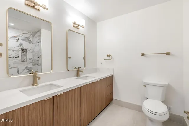 a bathroom with a double vanity sink toilet and a mirror