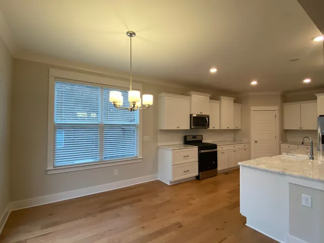 a kitchen with kitchen island granite countertop a stove a sink a center island a refrigerator and a wooden floor