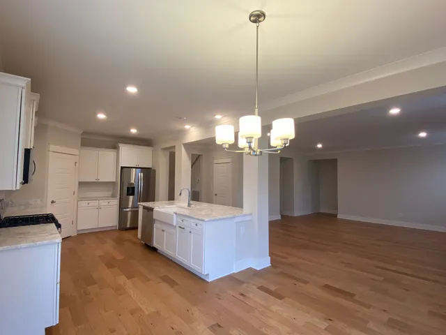 a large kitchen with kitchen island a island a stove a oven a refrigerator and a chandelier