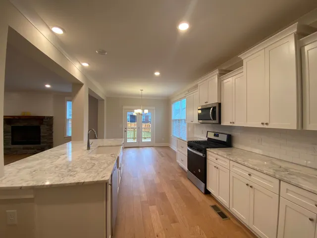 a large kitchen with stainless steel appliances granite countertop a large counter top and a stove top oven