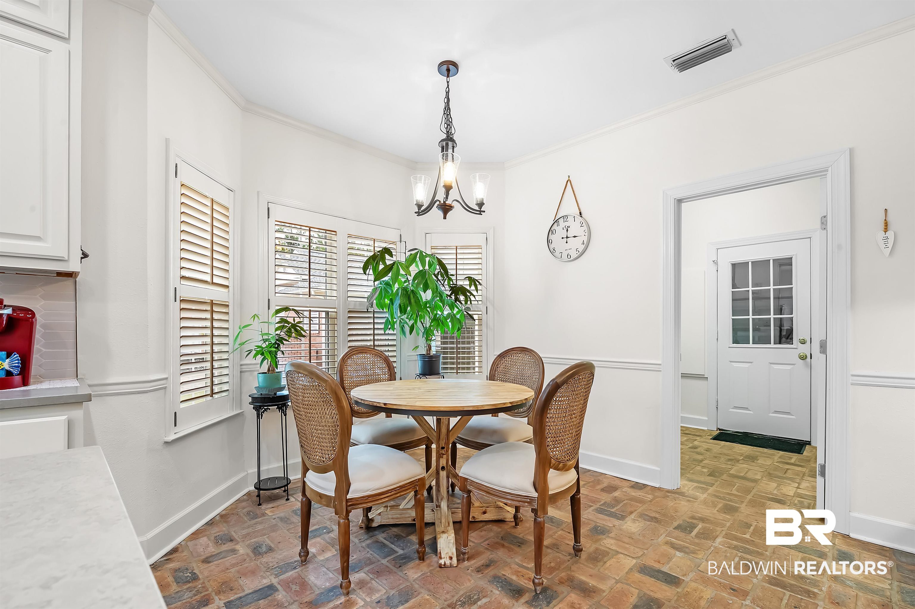 8915 Bay Point Drive Elberta, AL 36530 - Photo 46 of 74 Dining room with baseboards, visible vents, brick floor, crown molding, and a chandelier