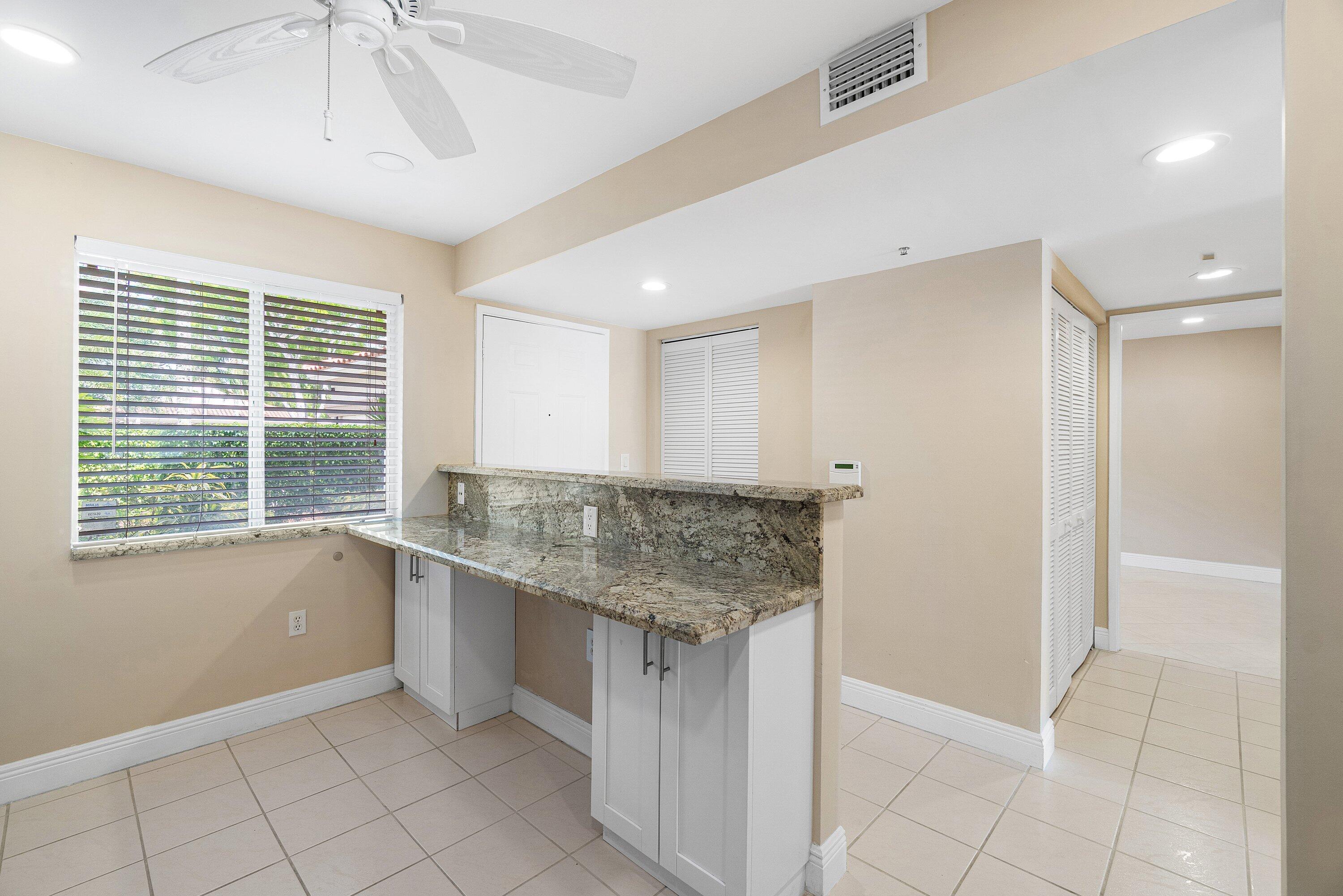 14096 Huntington Pointe Drive, Unit 106 Delray Beach, FL 33484 - Photo 21 of 47 a kitchen with granite countertop a sink and a white cabinets