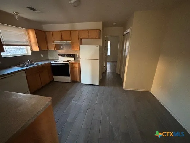 a kitchen with a refrigerator wooden floor and a sink