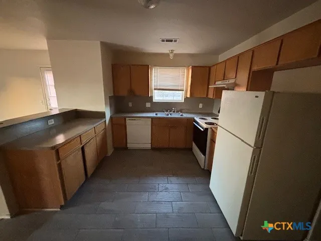 a kitchen with stainless steel appliances granite countertop a refrigerator a stove a sink and a microwave