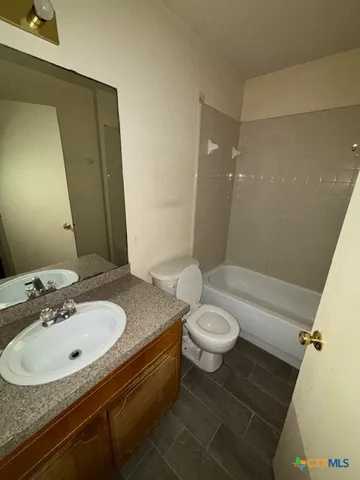 a bathroom with a granite countertop sink toilet and mirror