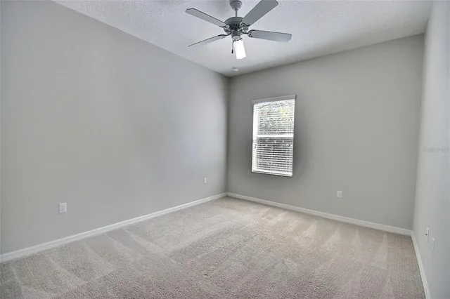 an empty room with a ceiling fan and a window