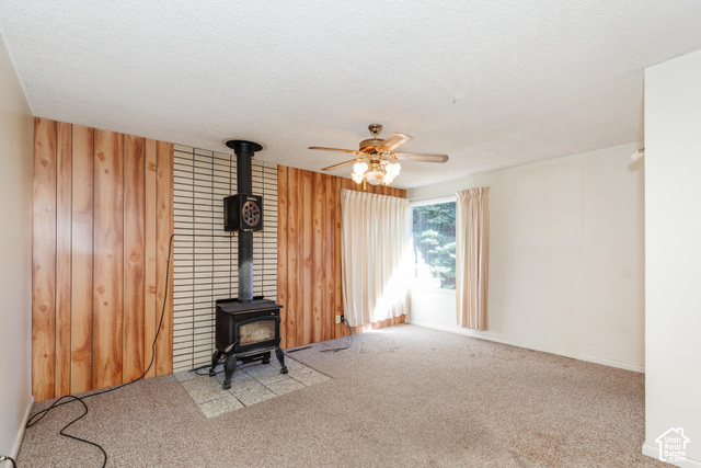 3959 Main Street Logan, UT 84321 - Photo 16 of 35 Wood-paneled accent wall with a cast iron wood-burning stove on a tiled hearth