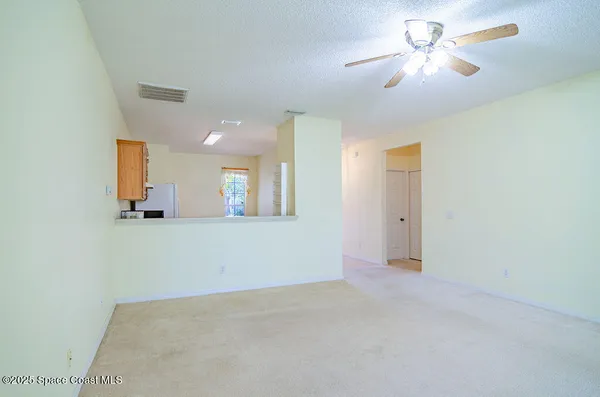 an empty room with a chandelier fan and windows
