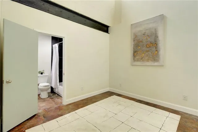 a view of a hallway with wooden floor and a bathroom