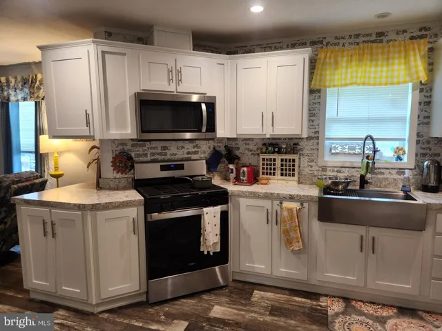 a kitchen with stainless steel appliances granite countertop a stove a sink and a microwave