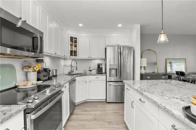 a kitchen with stainless steel appliances granite countertop a refrigerator a stove top oven a sink and dishwasher