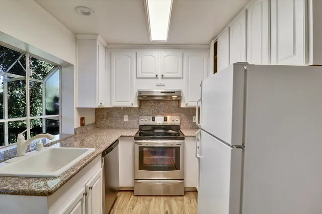 a kitchen with granite countertop a refrigerator stove and sink