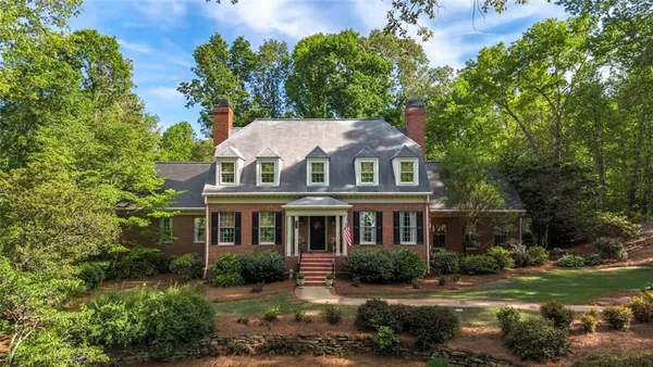 a view of a big house with a big yard and large trees