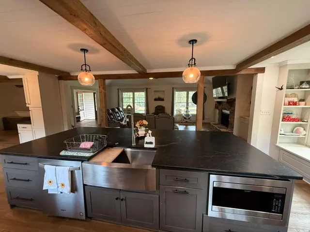 a large kitchen with granite countertop a large counter top space a sink and stainless steel appliances