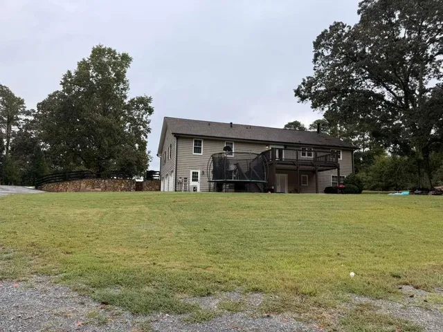 a view of a white house with a yard and large trees