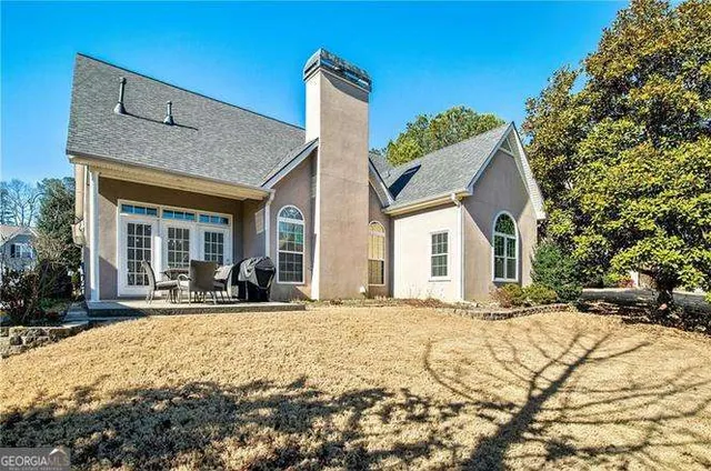 a view of a white house with a yard and lawn chairs