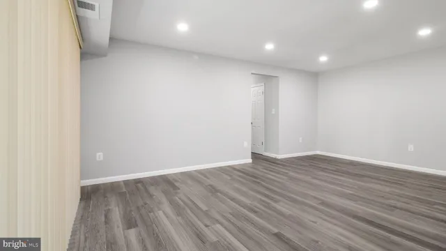 a view of an empty room with wooden floor and closet