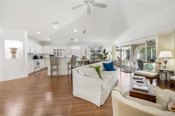 a living room with couches and kitchen view with wooden floor