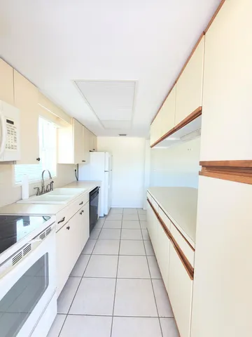 a large white kitchen with a sink and dishwasher stove top oven