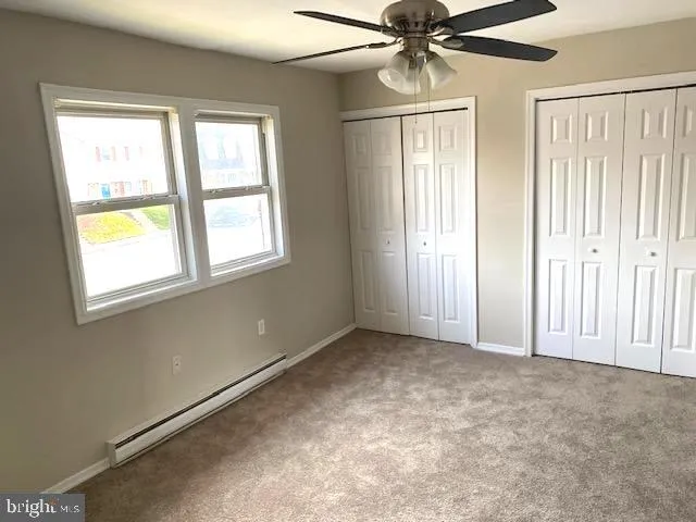 an empty room with windows and fan