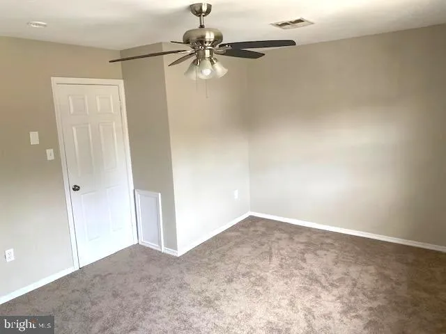 an empty room with a ceiling fan and carpet