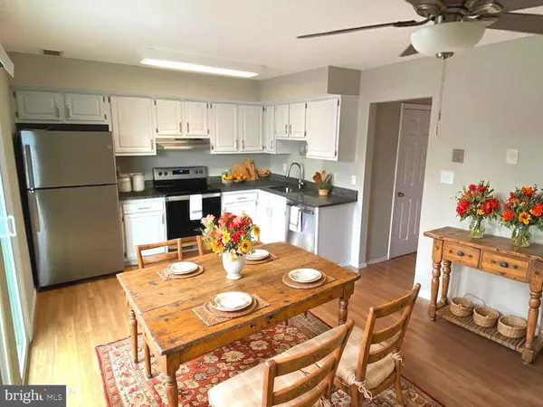a kitchen with stainless steel appliances granite countertop a refrigerator a stove top oven a dining table and chairs