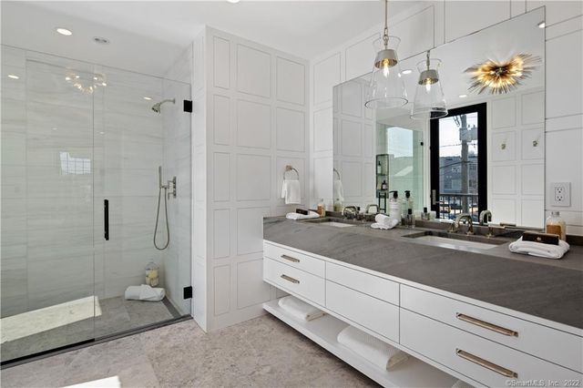 a spacious bathroom with a double vanity sink a large mirror and a shower