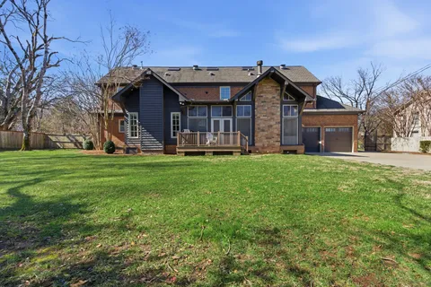 a view of a house with a big yard and large trees