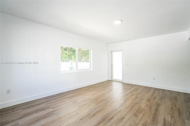an empty room with wooden floor and window